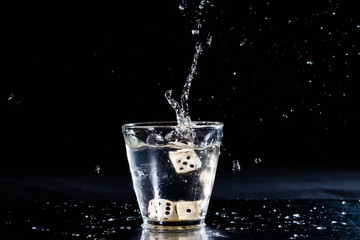 vaso splash con agua fondo negro y dados