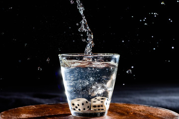 vaso splash con agua fondo negro y dados