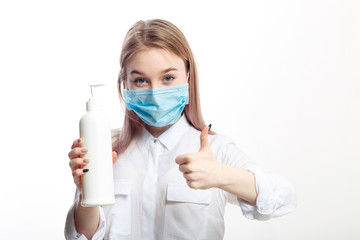 young blonde girl in a white blouse and a medical mask uses an antiseptic on a white background