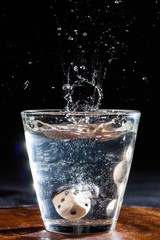 vaso splash con agua fondo negro y dados
