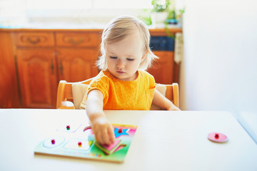 Adorable toddler girl doing wooden puzzle