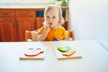 Adorable toddler girl doing wooden puzzle