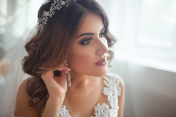 A young woman touches her wedding earrings with her hands.