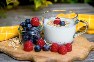 Eating a healthy breakfast. Yogurt, granola, chia seeds, fresh and dry fruits, blueberries, raspberries in a transparent. Clean food, diet, detox, vegetarian food concept.