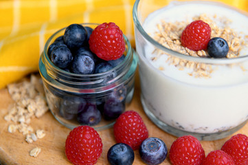 Eating a healthy breakfast. Yogurt, granola, chia seeds, fresh and dry fruits, blueberries, raspberries in a transparent. Clean food, diet, detox, vegetarian food concept.