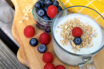 Eating a healthy breakfast. Yogurt, granola, chia seeds, fresh and dry fruits, blueberries, raspberries in a transparent. Clean food, diet, detox, vegetarian food concept.