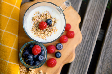 Eating a healthy breakfast. Yogurt, granola, chia seeds, fresh and dry fruits, blueberries, raspberries in a transparent. Clean food, diet, detox, vegetarian food concept.