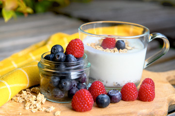 Eating a healthy breakfast. Yogurt, granola, chia seeds, fresh and dry fruits, blueberries, raspberries in a transparent. Clean food, diet, detox, vegetarian food concept.