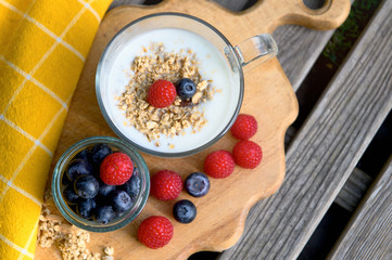 Eating a healthy breakfast. Yogurt, granola, chia seeds, fresh and dry fruits, blueberries, raspberries in a transparent. Clean food, diet, detox, vegetarian food concept.
