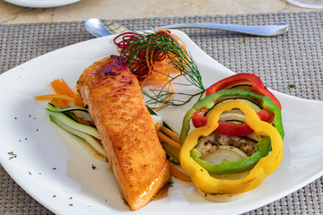 Salmon filet with vegetables on  a white plate