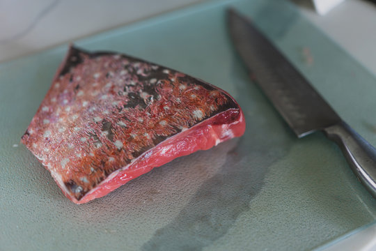 raw fish on a cutting board with knife