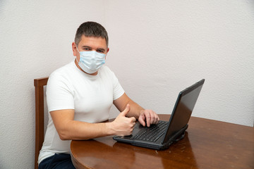 Fototapeta na wymiar Businessman in hygienic mask working on laptop, home self isolation to prevent contagious disease coronavirus, 2019-nCoV, flu epidemic.