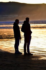 Brothers in silhouette on the beach at sunset