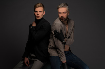 Male models posing on grey background in suits. Isolated.