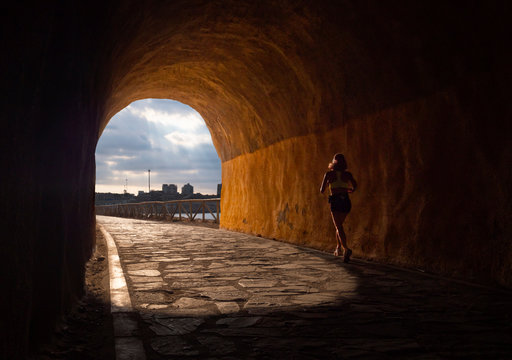 Mujer atravesando un t&uacute;nel de tren corriendo hacia la luz