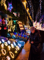 mujer con gorro de lana mirando a una tienda llena de luces en Alsacia