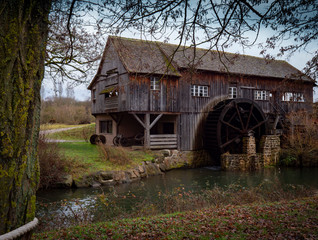 viejo molino de madera con aspas de agua  en ambiente de otoño invernal junto a arroyo