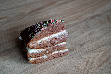 Chocolate Cake. Piece of Cake on a Plate. Sweet food. Sweet dessert. Wooden background. On a wooden stand. Close up. With place for writing text