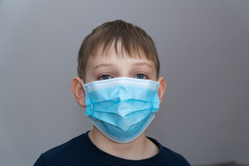 Depressed unhapped boy in blue medical mask in coronavirus COVID19 quarantine at home. Epidemic control of coronavirus infection. Sud, sorrowful, depressed child in mask home quarantine Isolated