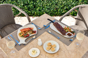 Salmon fillet with vegetables, churrasco beef meat with a green salad on a restaurant table