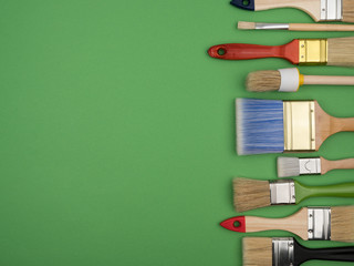 Set of different brushes for painting on a green background.