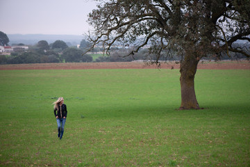 Donna passeggia in un prato attorno a un albero di quercia nella campagna in Puglia. Relax nella...