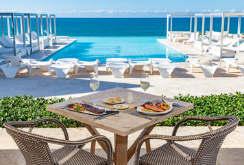 Oceanfront restaurant table, pool and ocean background, food and drinks, bread and butter