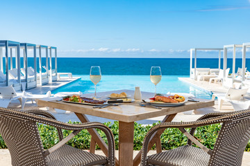 Oceanfront restaurant table, pool and ocean background, food and drinks, bread and butter - obrazy, fototapety, plakaty