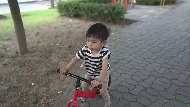 The boy trained to play a balance bike with her older sister tasing care of the garden