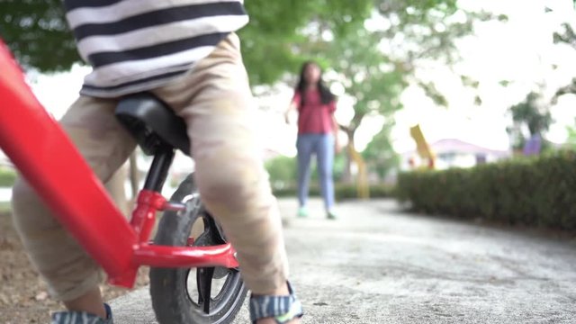The boy trained to play a balance bike with her older sister tasing care of the garden