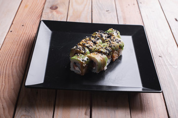 Salmon sushi on a square black plate on a dark wooden background