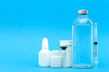 pharmaceuticals for the treatment of diseases unlabeled plastic and glass bottles with pills and vaccines on a blue background with copy space.