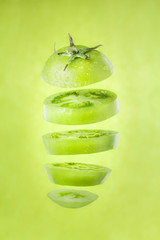 Green tomato slices suspended in the air, close-up