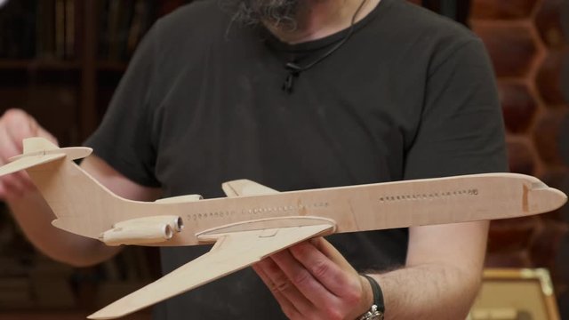 teacher gives masterclass holding and showing for camera handmade soviet plane wooden model close view slow motion