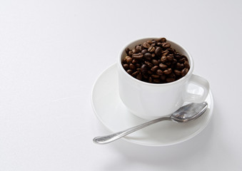 coffee beans in a white cup on a white background.