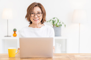 部屋でラップトップコンピューターを見るシニア女性