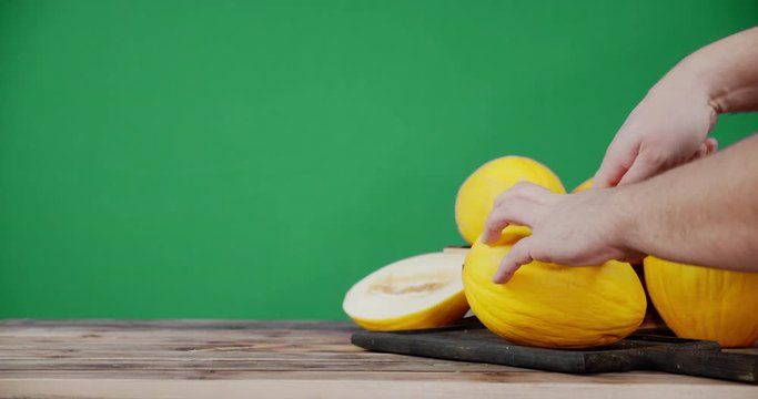Hands men cut the melon into two halves.