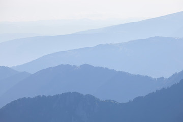 Naklejka premium Mountains in the morning haze, blue natural background