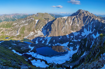 View from the top of the mountain valley in the evening. Snow, rocks and lake. Traveling in the mountains, trekking
