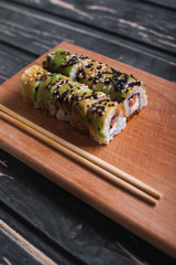 Sushi with salmon on a wooden board on a dark wooden background
