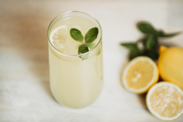 Refreshment Summer drink. Traditional lemonade. Ripe yellow lemon citrus fruit with green leaf and white wooden background. Lemons with clipping path.