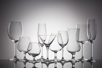 Empty clear glassware. Set of glasses for different alcoholic drinks and cocktails on dark gray background.