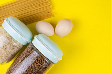 Food stock for quarantine isolation period on yellow background. Rice, egg, buckwheat, spaghetti. Food delivery, Donation. Copyspace