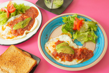 Huevos, recién horneados con una salsa de tomate y una ensalada con aguacate, para una dieta keto o personas fit.