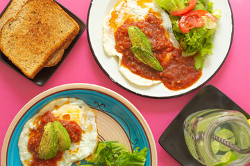 Huevos, recién horneados con una salsa de tomate y una ensalada con aguacate, para una dieta keto o personas fit.