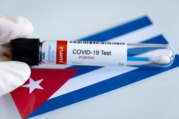 Testing for presence of coronavirus in Cuba. Tube containing a swab sample that has tested positive for COVID-19. Cuban flag in the background.