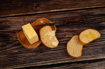 Fresh wheat toast with butter and a piece of butter in a wooden butter dish on a wooden background. Close up.