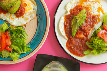 Huevos, recién horneados con una salsa de tomate y una ensalada con aguacate, para una dieta keto o personas fit.