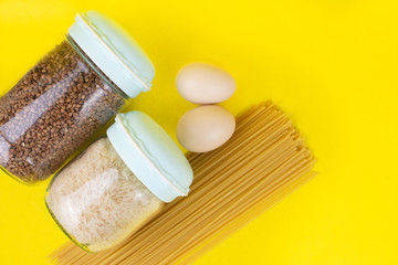 Food stock for quarantine isolation period on yellow background. Rice, egg, buckwheat, spaghetti. Food delivery, Donation. Copyspace