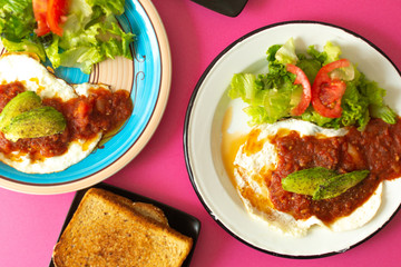 Huevos, recién horneados con una salsa de tomate y una ensalada con aguacate, para una dieta keto o personas fit.
